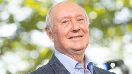 A photo of Sir Kenneth Calman smiling wearing a suit and shirt