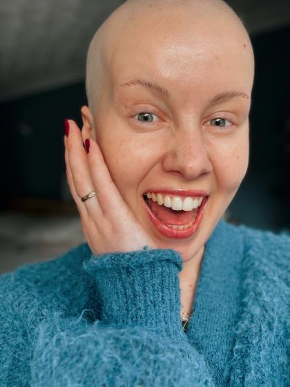 Claire smiling taking a selfie, she has no hair following her chemotherapy treatment