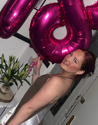 A photo of Taegan on her 18th birthday holding pink 1 and 8 balloons